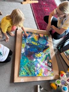 A mum and her toddler are working on a canvas together.